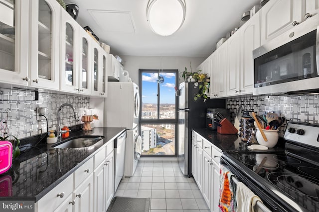 kitchen featuring stacked washer / dryer, sink, white cabinets, light tile patterned floors, and stainless steel appliances