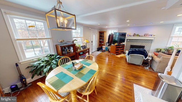 dining room featuring a tiled fireplace, hardwood / wood-style floors, and ornamental molding