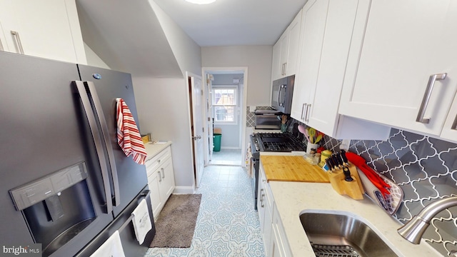 kitchen with tasteful backsplash, white cabinetry, appliances with stainless steel finishes, and sink