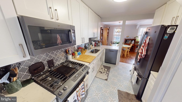 kitchen featuring stainless steel appliances, sink, white cabinets, and decorative backsplash