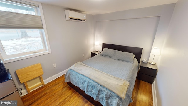 bedroom with hardwood / wood-style flooring and a wall mounted air conditioner