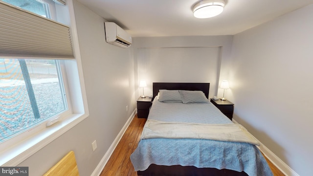 bedroom featuring wood-type flooring and an AC wall unit