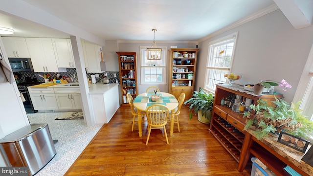 dining area featuring crown molding, sink, and light wood-type flooring