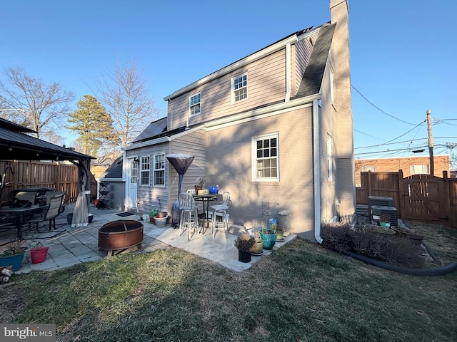 rear view of property featuring an outdoor fire pit, a yard, and a patio