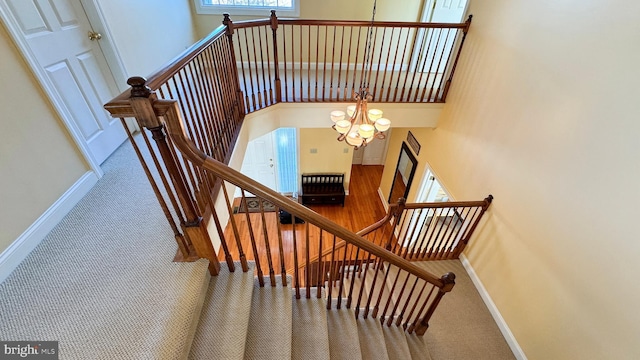 staircase featuring a high ceiling, carpet, and a chandelier