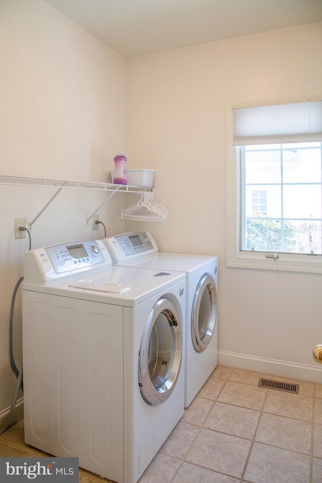 clothes washing area with washing machine and dryer and light tile patterned floors