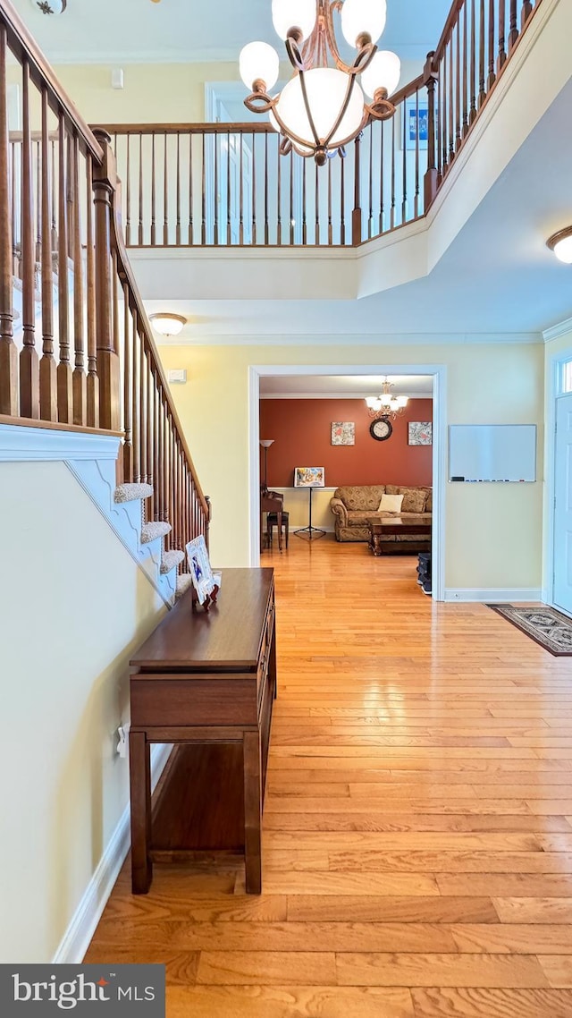 interior space featuring a high ceiling, ornamental molding, a chandelier, and light hardwood / wood-style floors