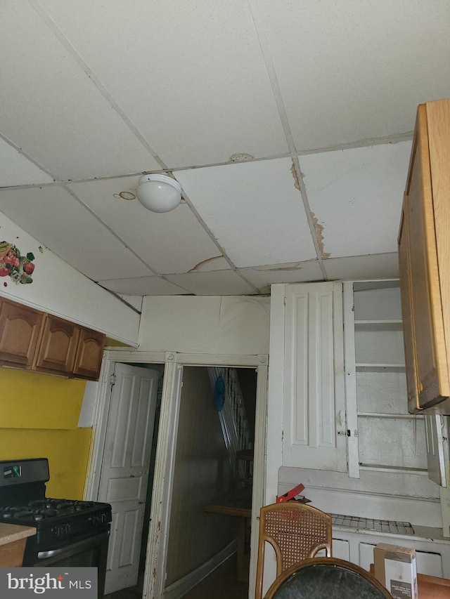 kitchen with black gas stove and a drop ceiling