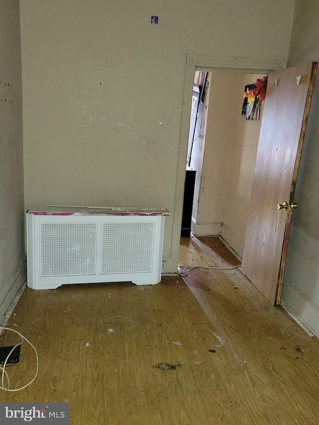 interior space with wood-type flooring and radiator heating unit