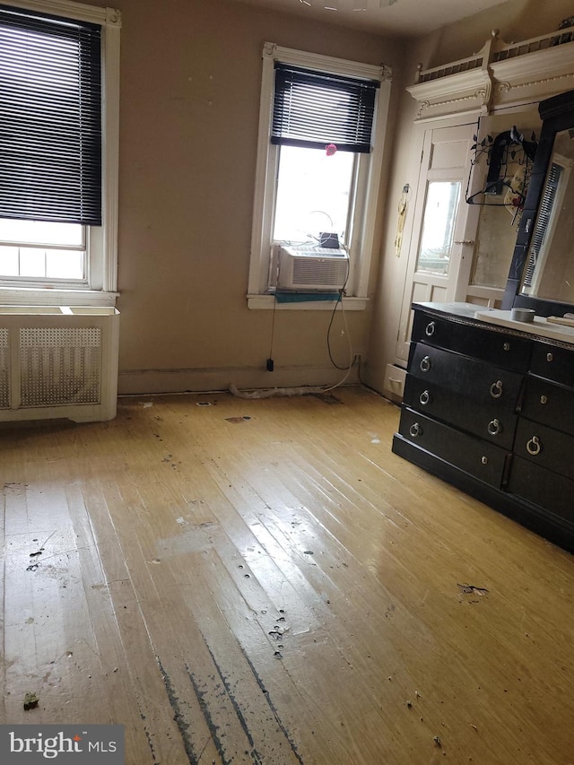 unfurnished bedroom featuring cooling unit and light wood-type flooring