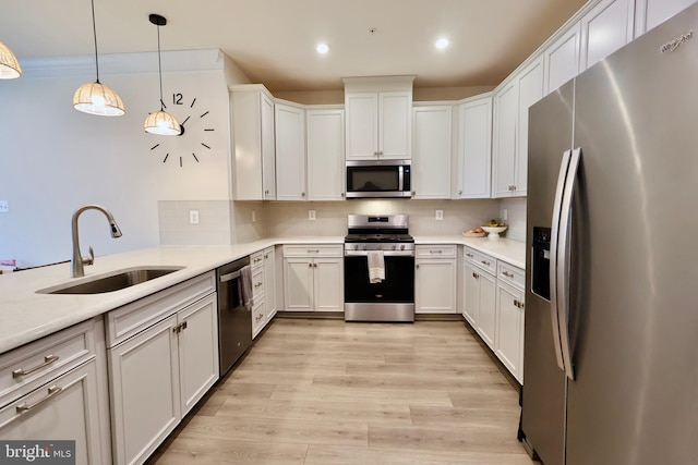 kitchen with a sink, white cabinets, appliances with stainless steel finishes, tasteful backsplash, and pendant lighting