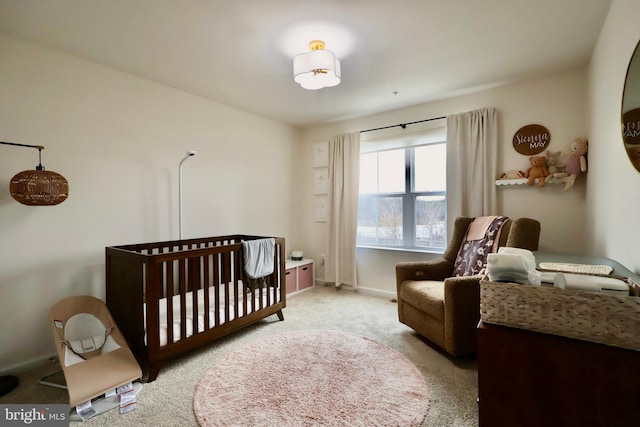 bedroom featuring a crib, light carpet, and baseboards