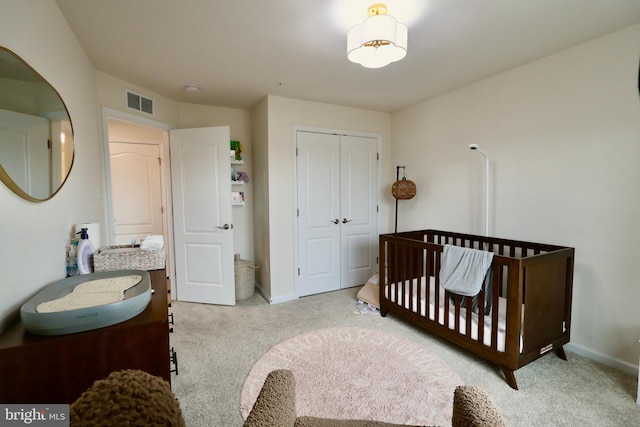 bedroom featuring a sink, visible vents, a closet, and light colored carpet