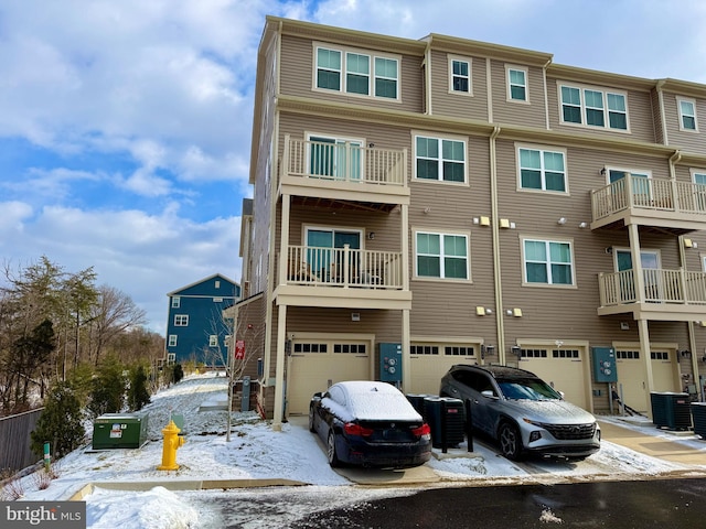 snow covered building featuring cooling unit and an attached garage