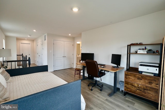 bedroom with a closet, visible vents, wood finished floors, and recessed lighting