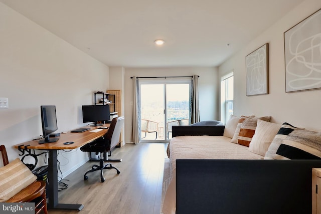 bedroom with light wood-style flooring, baseboards, and access to outside