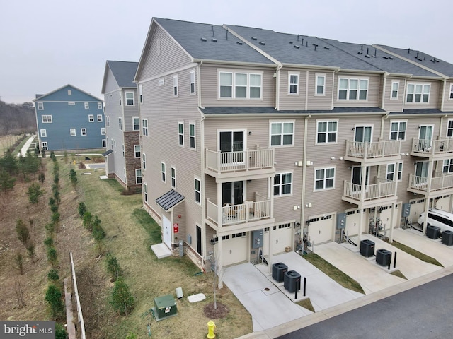 view of building exterior featuring cooling unit, driveway, and an attached garage