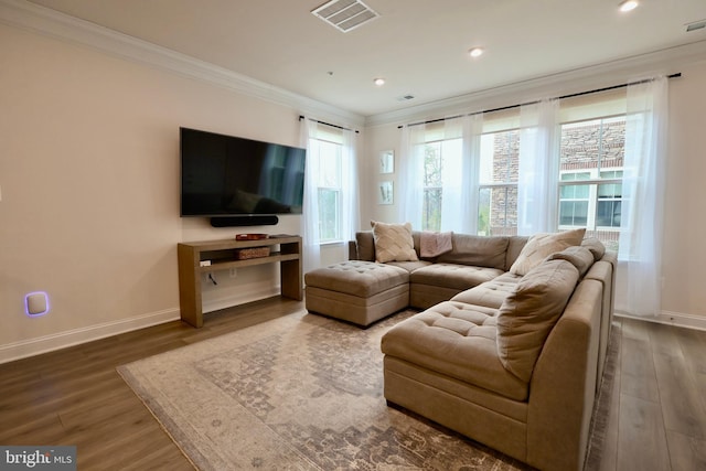 living area featuring baseboards, visible vents, wood finished floors, and ornamental molding