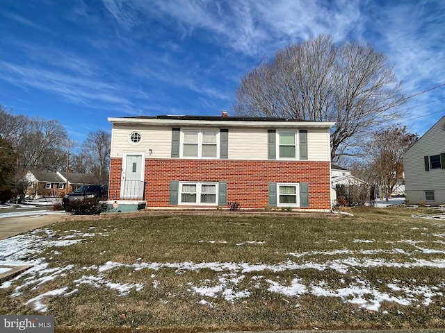 raised ranch featuring brick siding and a lawn