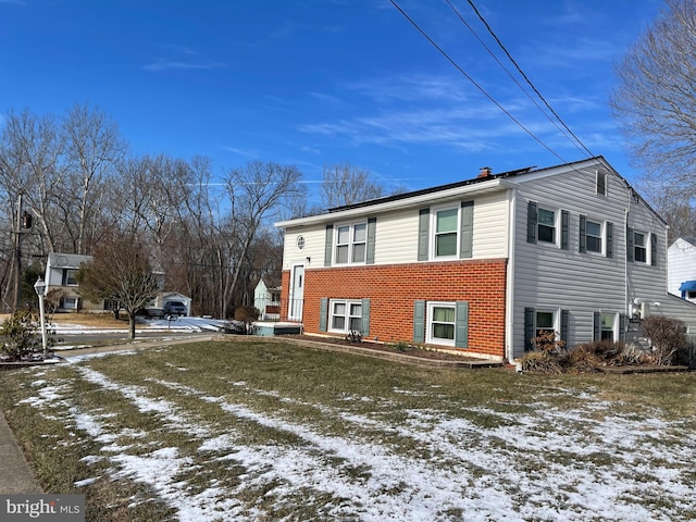 view of snowy exterior with a yard and brick siding