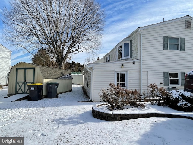 view of snow covered exterior featuring a storage shed and an outbuilding