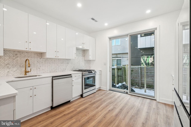 kitchen featuring light hardwood / wood-style flooring, sink, white cabinets, decorative backsplash, and stainless steel appliances