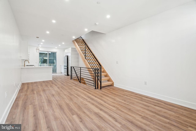 unfurnished living room with sink and light wood-type flooring