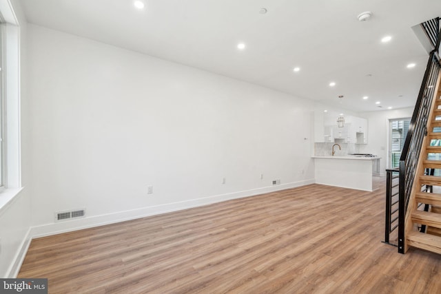 unfurnished living room with sink and light wood-type flooring