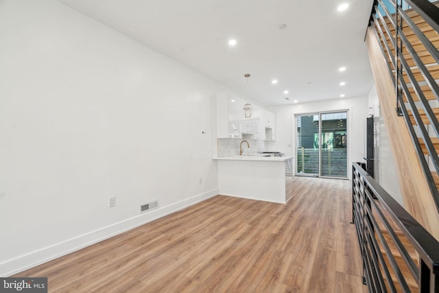 unfurnished living room featuring sink and light hardwood / wood-style floors