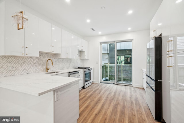 kitchen with gas range, sink, white cabinets, and kitchen peninsula