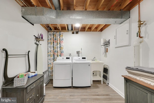 clothes washing area featuring light hardwood / wood-style flooring and washer and dryer