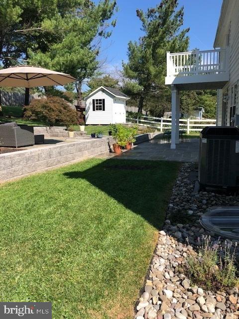 view of yard featuring cooling unit, a storage shed, a patio, and a balcony