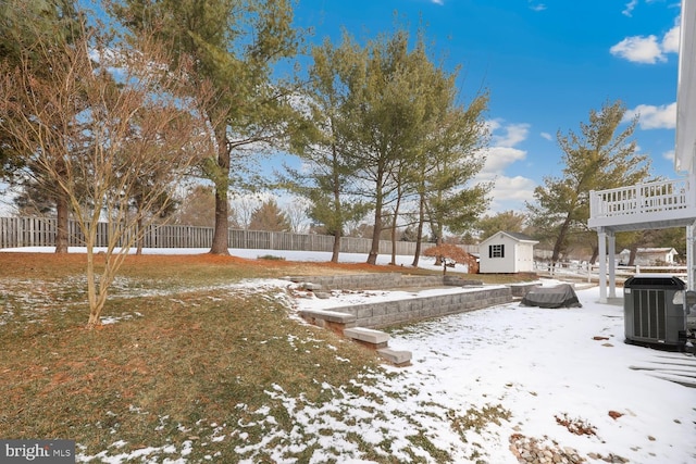 snowy yard with cooling unit and a shed