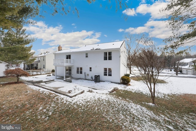 snow covered rear of property featuring central AC unit and a balcony