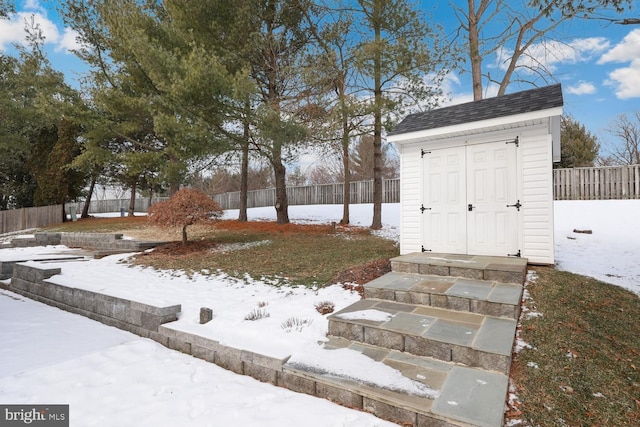 yard covered in snow featuring a storage shed