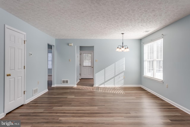 unfurnished room featuring a notable chandelier, dark hardwood / wood-style flooring, and a textured ceiling