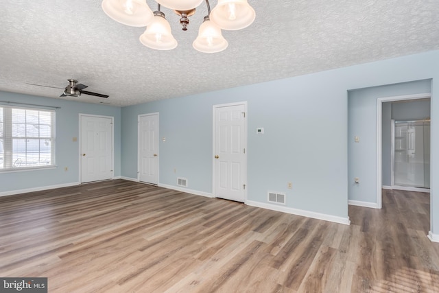 unfurnished room with ceiling fan with notable chandelier, hardwood / wood-style floors, and a textured ceiling