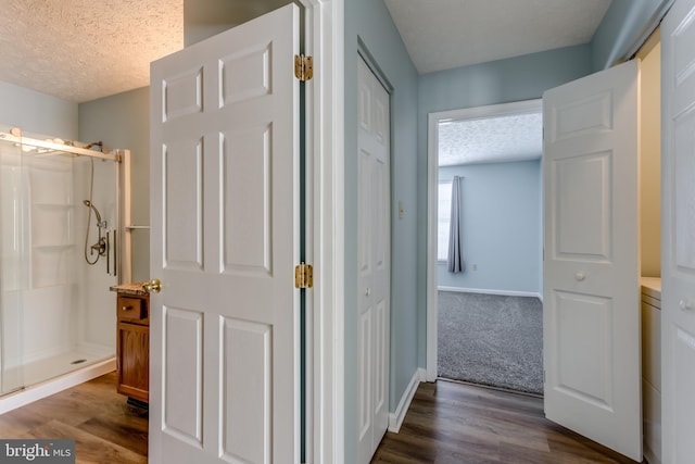 hall with a textured ceiling and dark hardwood / wood-style floors