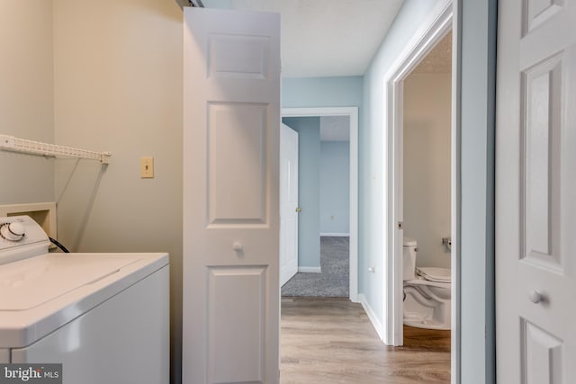 clothes washing area with light hardwood / wood-style floors and washer / clothes dryer