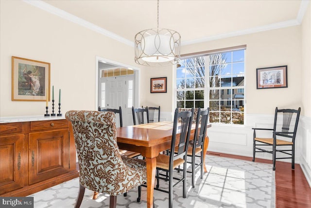 dining area featuring a notable chandelier, ornamental molding, and light wood-type flooring