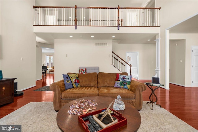 living room featuring hardwood / wood-style flooring, a towering ceiling, and decorative columns