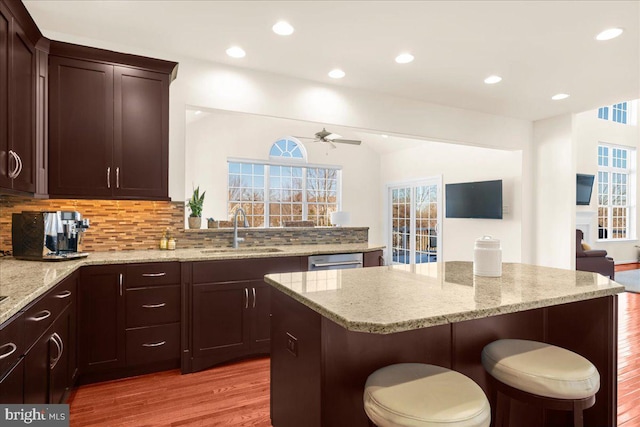 kitchen with tasteful backsplash, a breakfast bar, sink, and light stone countertops