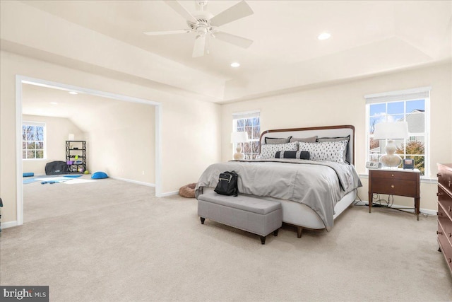 carpeted bedroom featuring ceiling fan, a raised ceiling, and multiple windows