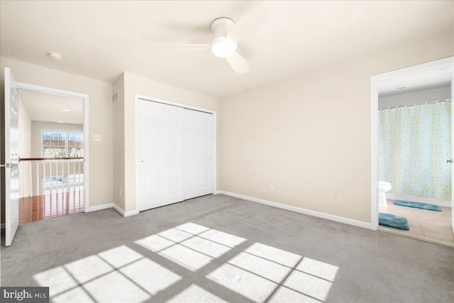 unfurnished bedroom featuring connected bathroom, light colored carpet, ceiling fan, and a closet