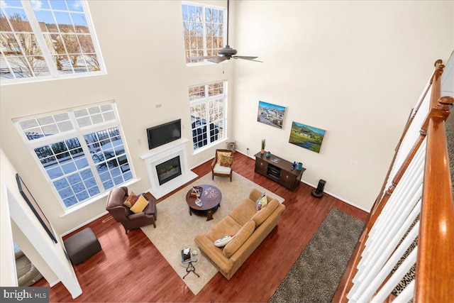 living room with dark wood-type flooring, a towering ceiling, and ceiling fan