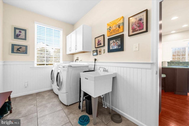 laundry room featuring washer and dryer, light tile patterned floors, and cabinets