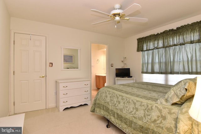 carpeted bedroom with ensuite bath and ceiling fan