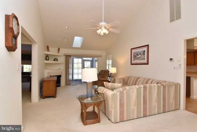 carpeted living room featuring ceiling fan, high vaulted ceiling, and a skylight