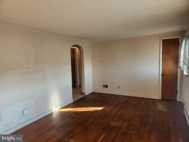 empty room with baseboard heating and dark wood-type flooring