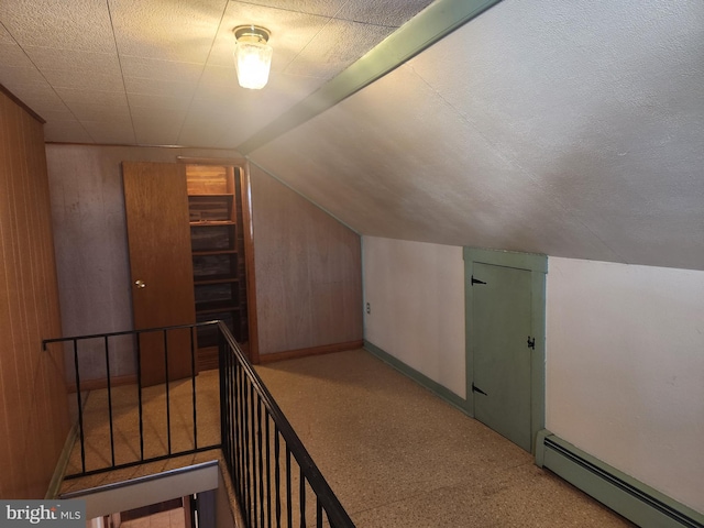 bonus room with wooden walls, baseboard heating, and lofted ceiling